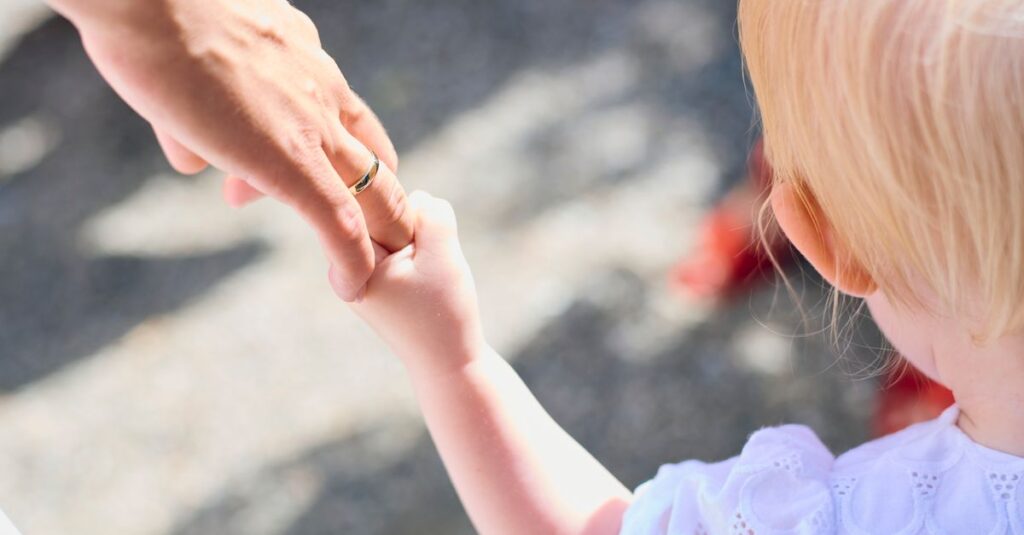 child holding parent hand airport