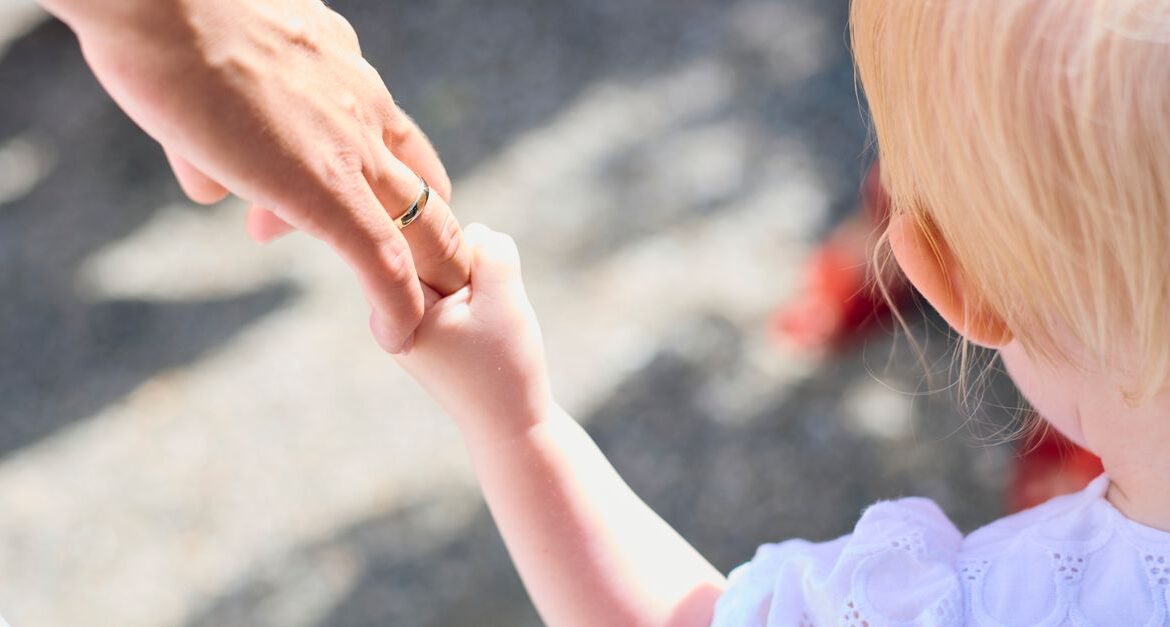 child holding parent hand airport